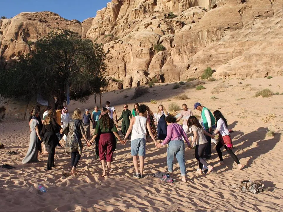 A circle of people holding hands in the desert