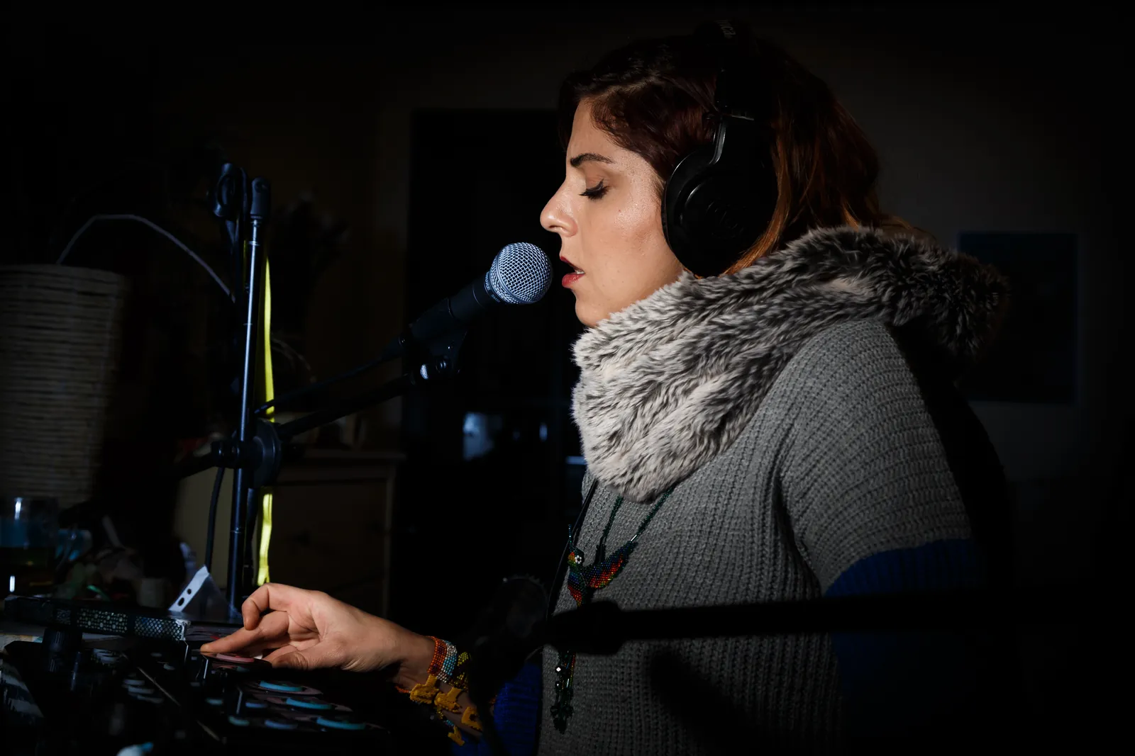 Rawan singing into a microphone at home, headphones on, eyes closed