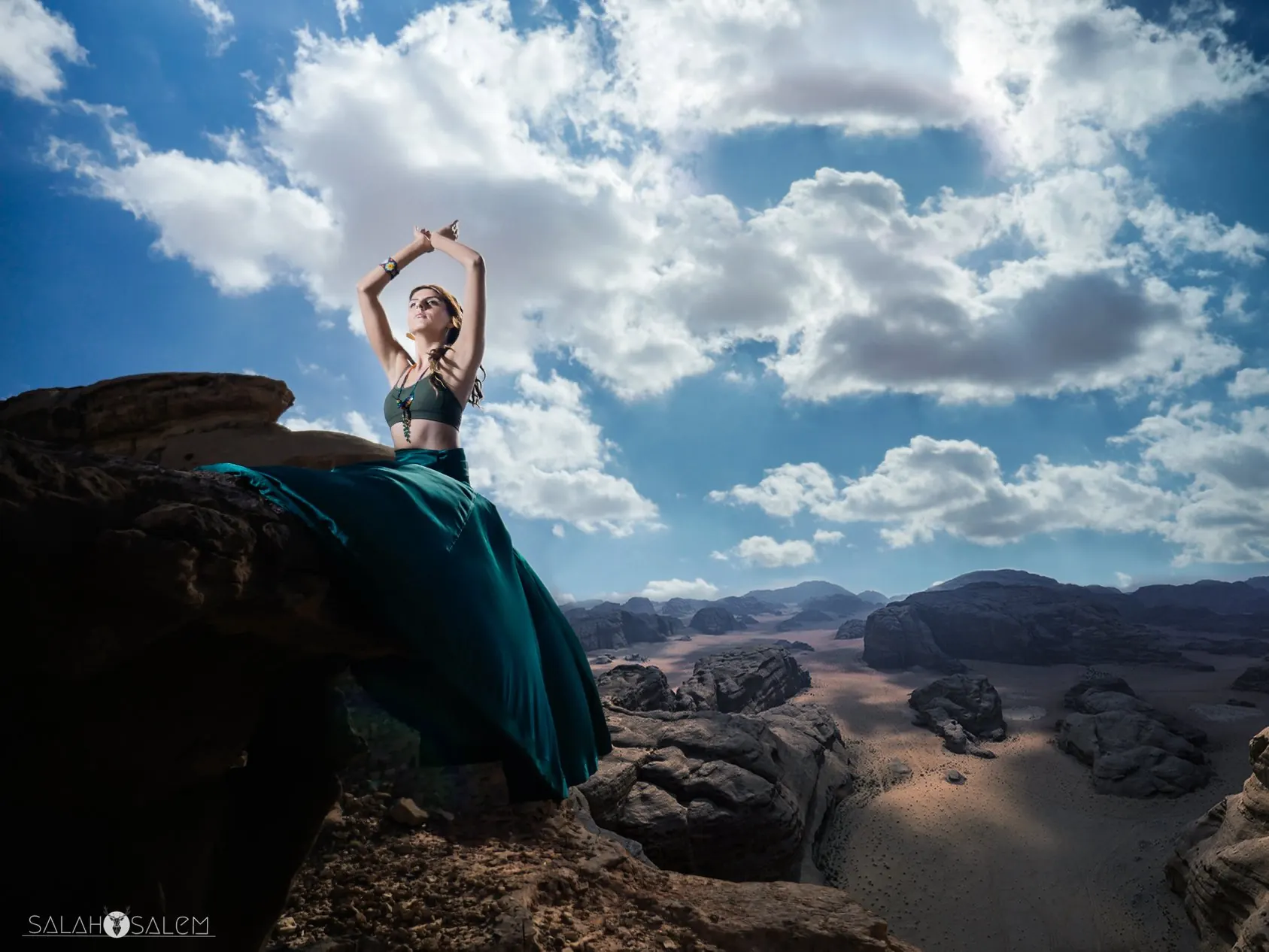 Rawan in a teal skirt on a cliff edge above the Wadi Rum desert