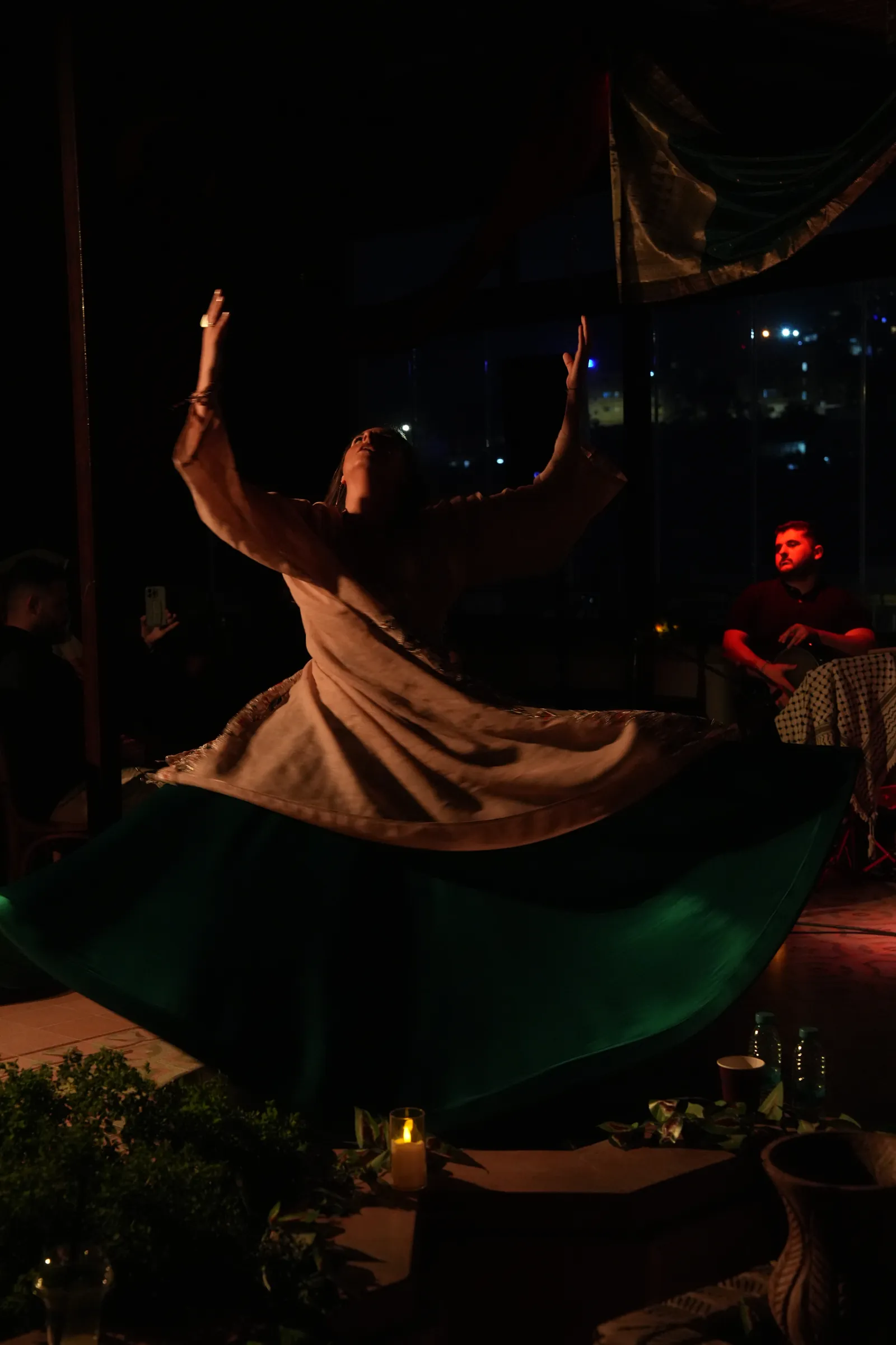 Rawan whirling by candlelight, arms raised, at Khafaya Al-Quloob, Bait Shocair, Amman