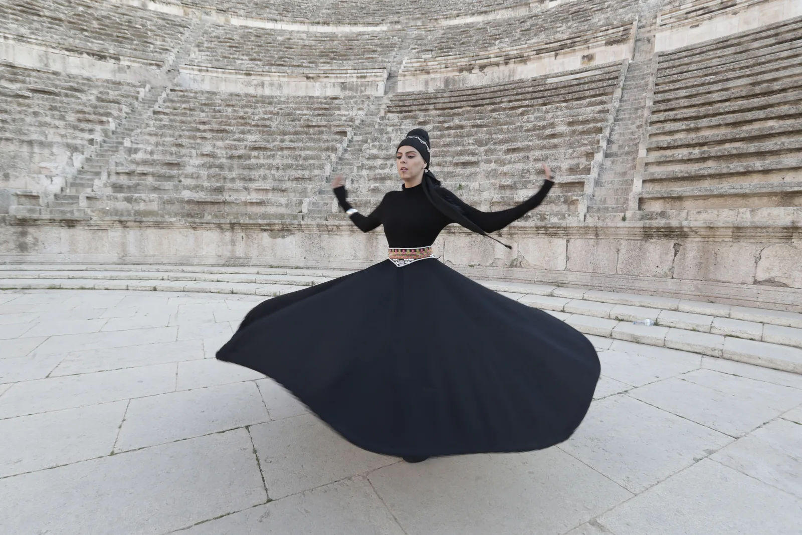 Rawan whirling in black, alone in the Roman Theatre, Amman